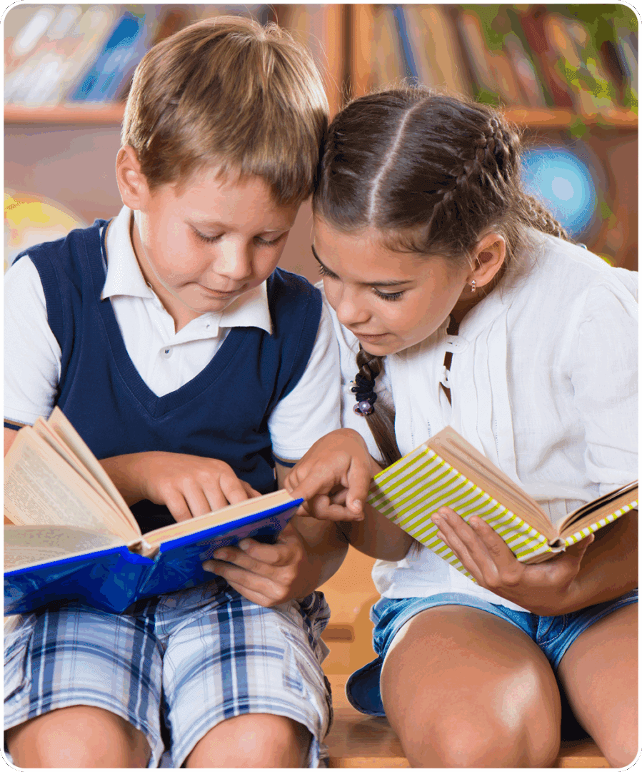 Two children reading books together in a classroom.